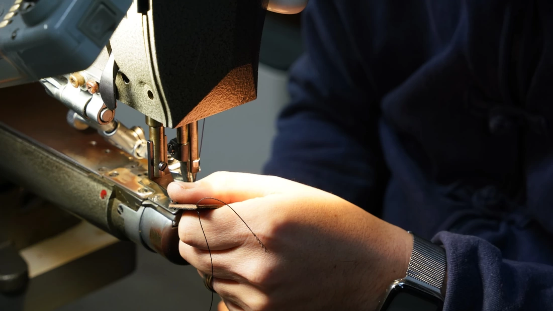 革の縫製用ミシンで職人がしおりを製作している様子
